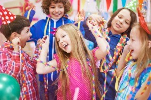 6 year old girl surrounded by friends with streamers, party blowers, and party hats