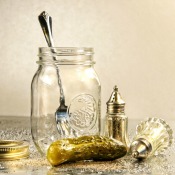 Pickle and old fashioned salt and pepper shakers next to an empty jar with a fork in it.
