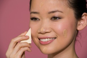 Woman applying foundation to skin with a make-up sponge