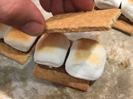 Placing the top cracker on a Smore.