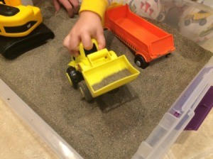 Indoor Sandbox - child's hand playing with bulldozer