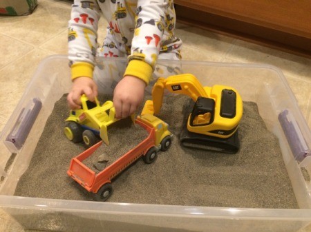 Indoor Sandbox - child playing with trucks in sandbox