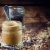 Jar of Dijon Mustard with spoon in front of a jar with black mustard