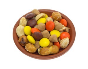 Snack mix of orange, brown, and yellow candies, butterscotch chips, pretzel nuggets, and nuts