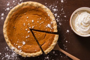 Photo of a pumpkin pie with small cracks in it and one slice being taken out.