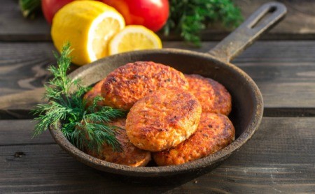 Salmon cakes in a cast iron pan with a sprig of dill.