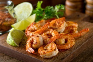 Canjun grilled shrimp with lime on a wood board.