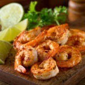 Canjun grilled shrimp with lime on a wood board.