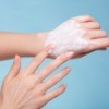 A person rubbing lotion on their hands.