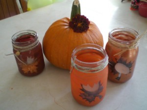 Three of the glass bottle candle holders arranged around a pumpkin.