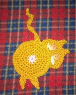 Crochet coaster of a cat looking back over its shoulder.