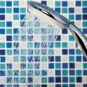 Shower head in blue tiled shower enclosure.