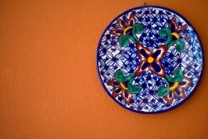 Decorative plate hanging on an orange wall.