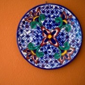 Decorative plate hanging on an orange wall.