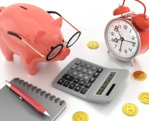 Piggy bank with glasses looking at a calculator.