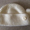 white knit hat with circle pin on folded up bottom