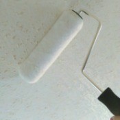 Using a paint roller to clean ceiling.