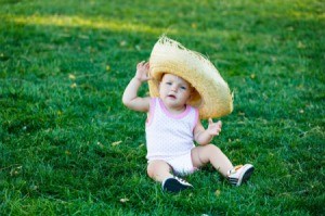 A baby wearing a overly large straw hat.