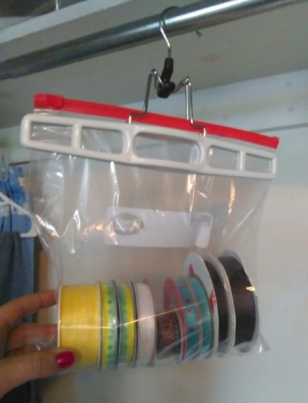 Ziploc bag of ribbon spools handing on a closet rod.