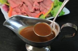 A ladle of au' jus served with roast beef.