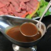 A ladle of au' jus served with roast beef.