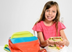 A girl eating lunch out of her lunch box.