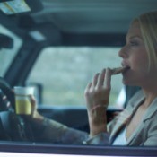 A woman eating breakfast in her car.