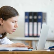 A woman looking at a small computer screen.