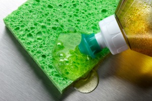 Dishwashing liquid being squeezed onto a sponge.