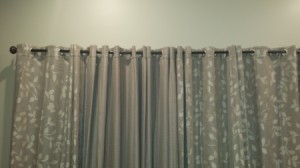 Grayish taupe curtains hanging against a neutral colored wall.