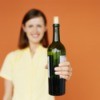 Woman holding out a partially empty bottle of wine with a cork partially reinserted