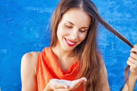 Woman holding a lock of hair in one hand and dry shampoo powder in the other