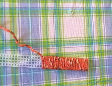 wrapping strip of plastic canvas with orange variegated yarn