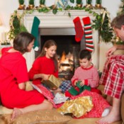 A young boy opening presents with his family on Christmas morning.