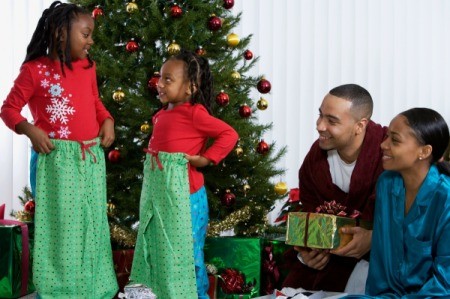 A family opening present on Christmas morning around the tree.