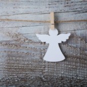 A paper angel cutout hanging from a clothespin.