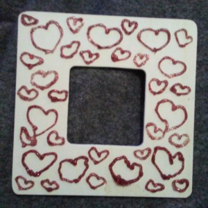 A wooden frame with red glitter hearts.