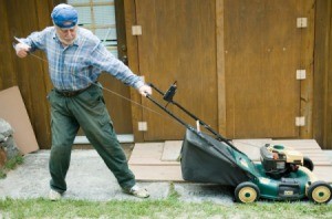 A man pulling on a cord to start a lawnmower.