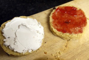A scone with cream on one side and jelly on the other.