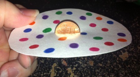 A penny in the center of a circular decorated paper.