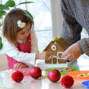 A toddler and her dad making a gingerbread house.