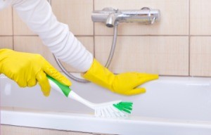 Someone cleaning a tub with rubber gloves on.