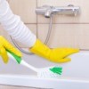 Someone cleaning a tub with rubber gloves on.