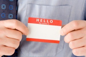 A man adhering a sticky name badge label to his dress shirt.