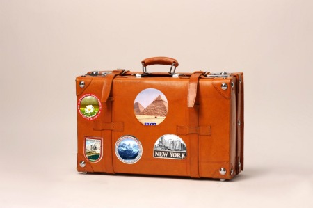 A leather suitcase with travel stickers.