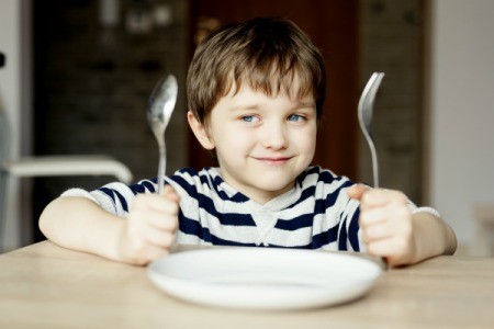 A boy waiting for dinner with an empty plate.