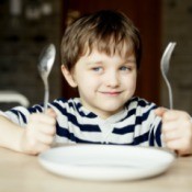 A boy waiting for dinner with an empty plate.