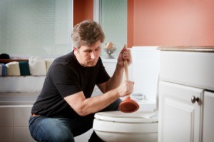 A man using a plunger in a toilet.