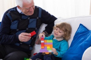 A grandfather playing blocks with his granddaughter.