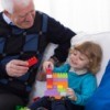 A grandfather playing blocks with his granddaughter.